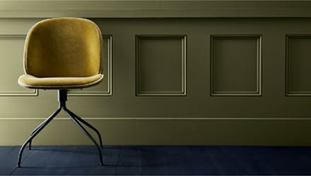 Velvet chair against dark green wood panelled wall